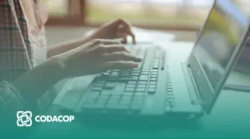 Manos de una persona escribiendo en una laptop en un entorno